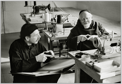 Photograph of Pre Robert, the tailor, (right), teaching Stanley Roseman Cistercian sign language in the tailor shop at the Abbey of La Trappe, 1998. The Trappist monk is showing the artist the sign for the word "bread." Photo  Ronald Davis